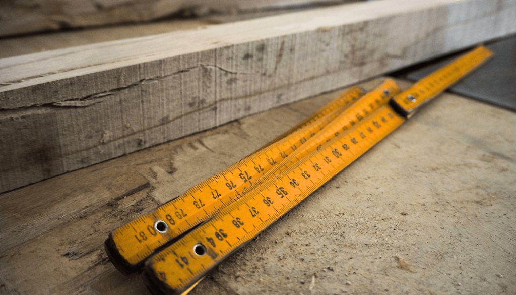 Drewniana składana miara stolarska położona na kawałku drewna
