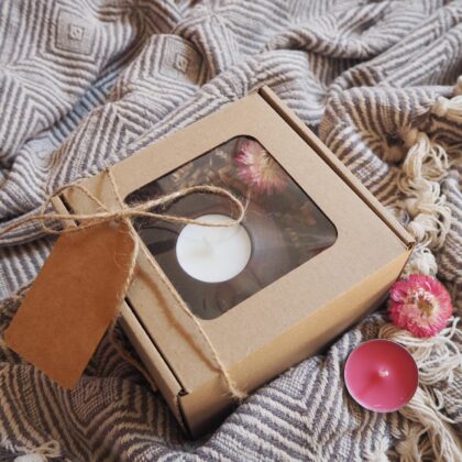Zestaw prezentowy opakowany w eko pudełko z okienkiem, ozdobione sznurkiem jutowym i eko bilecikiem na życzenia. W środku znajduje się drewniany świecznik z białą świecą podgrzewacz wraz z ozdobnym suszonym różowym kwiatem.