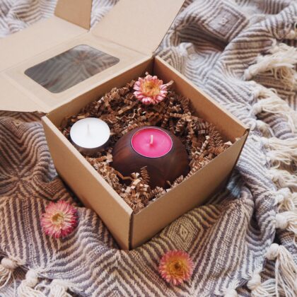 Box prezentowy, w eko pudełku znajduje się drewniany świecznik na tealighty z różową świecą. Obok biała świeca podgrzewacz i suszony różowy kwiat.